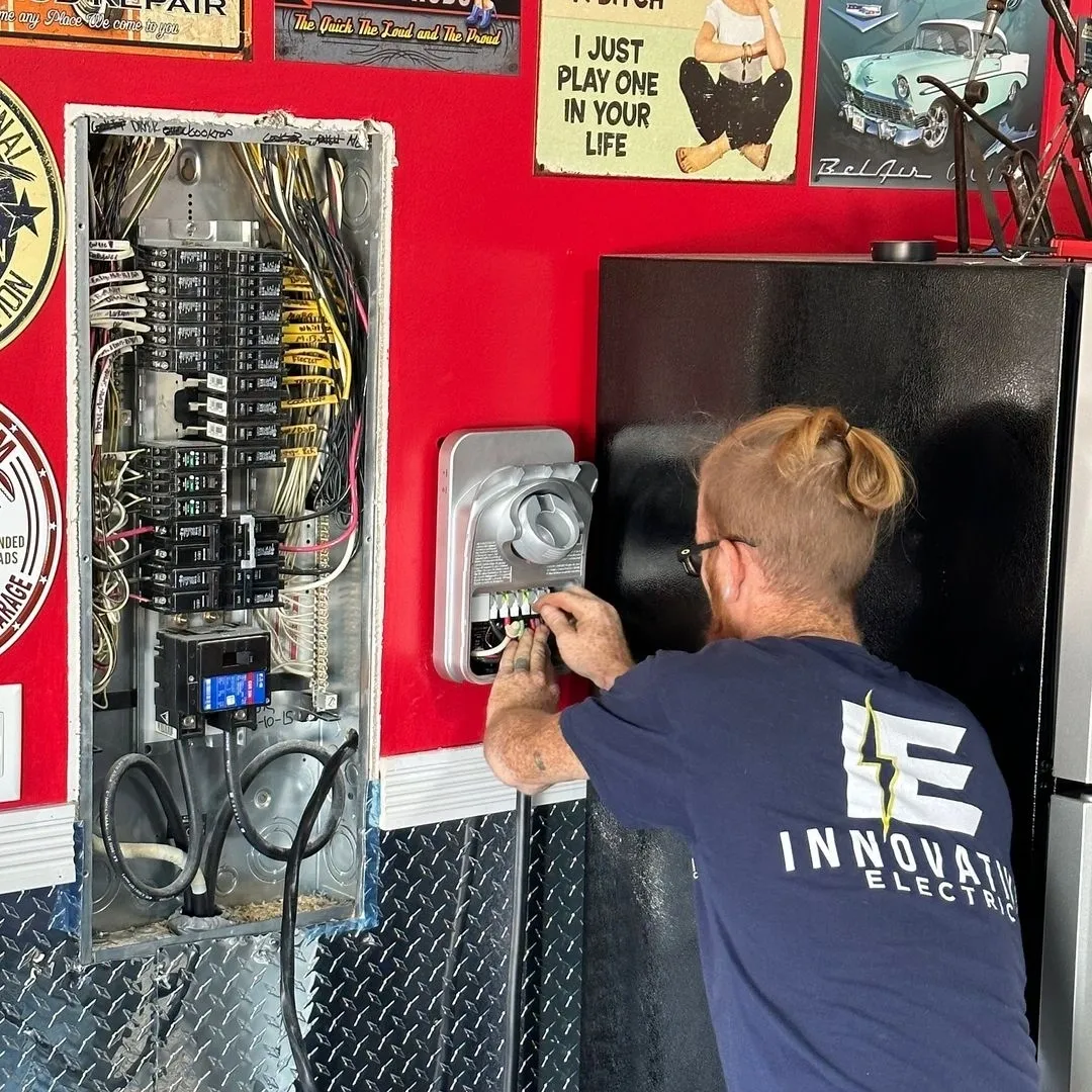 Electrician working on a red wall with a circuit breaker and electric meter, surrounded by vintage car posters. The scene conveys focus and expertise.